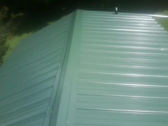 New green metal panels meeting at the ridge of a roof — Flat Roof Repair work by our crew in Los Lunas