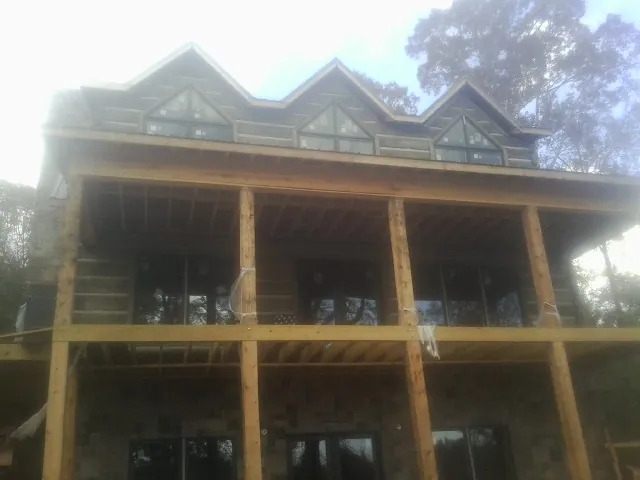Dormers and porch framing on a large log home under construction — Roof Coating work by our crew in Los Lunas