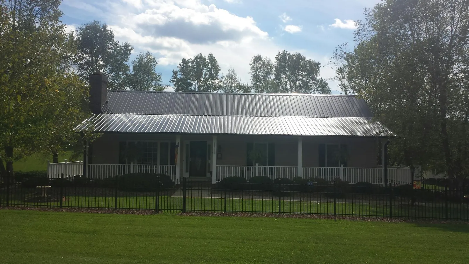 Gray metal roof on a brick ranch with a full width front porch — Gutter Guard Installation work by our crew in Los Lunas