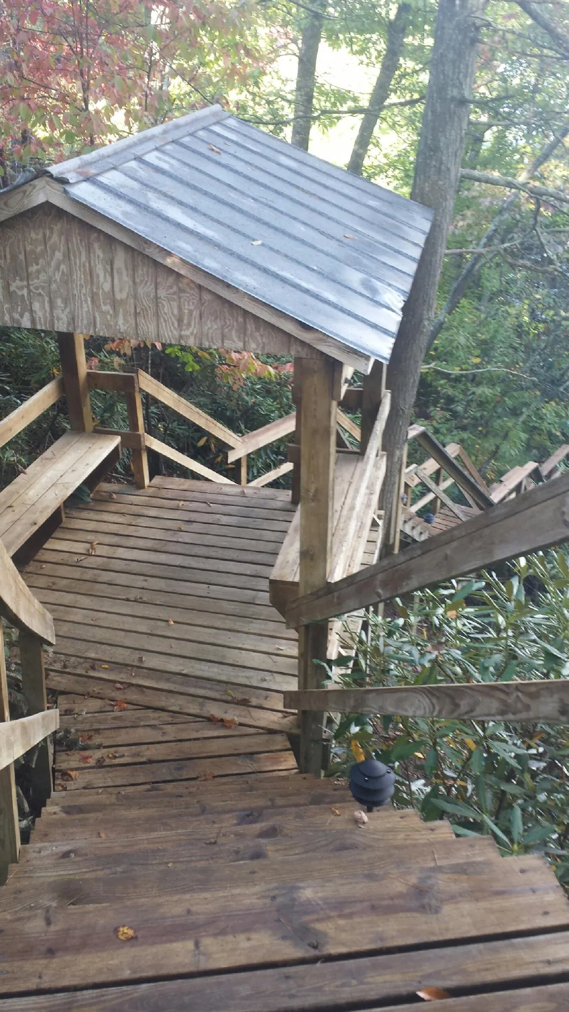 Metal roofed shelter over wooden steps on a wooded walkway — Skylight Repair & Installation work by our crew in Los Lunas