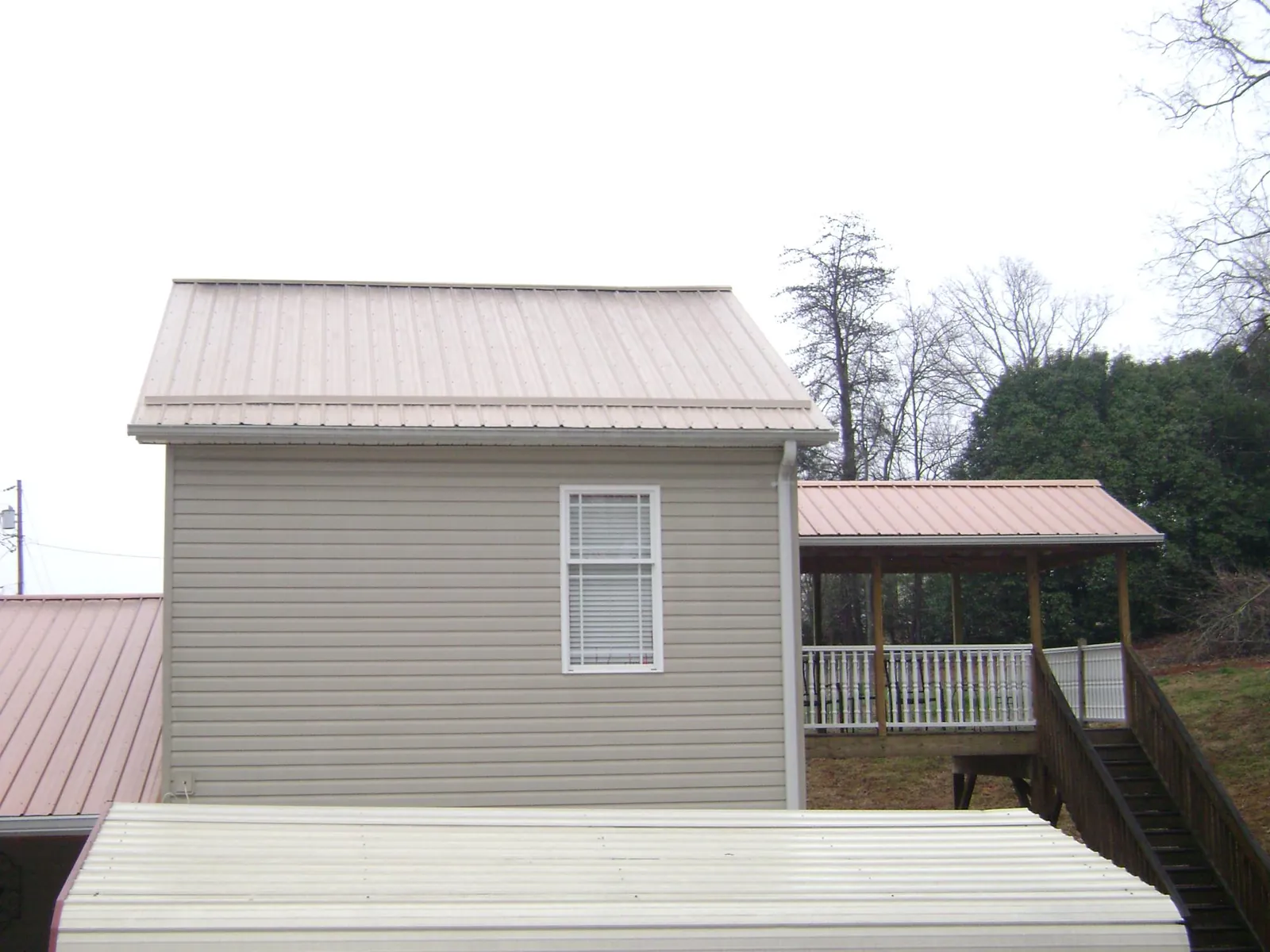 Tan metal roofs on a two story addition and attached porch, from a Roof Replacement job in Los Lunas
