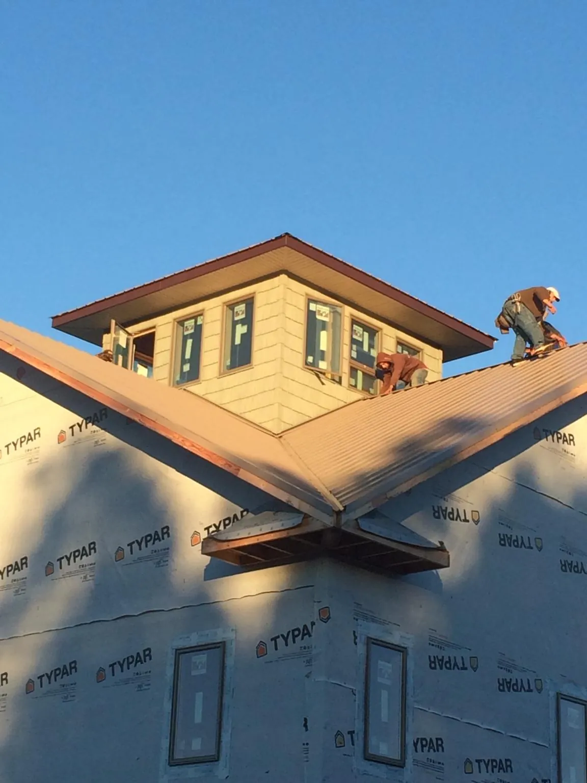 Roofers working around a rooftop cupola on a new metal roof at sunset — Roof Waterproofing in Los Lunas by Roofing Brothers